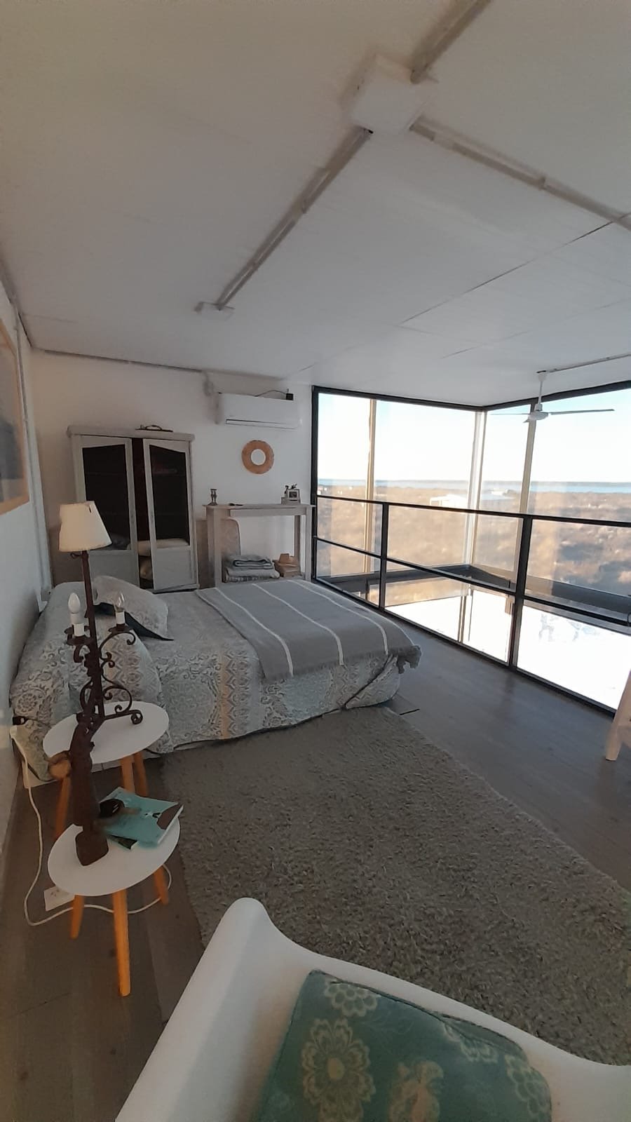 Interior de un módulo habitacional de doble piso con entrepiso, dormitorio y ventanal completo
